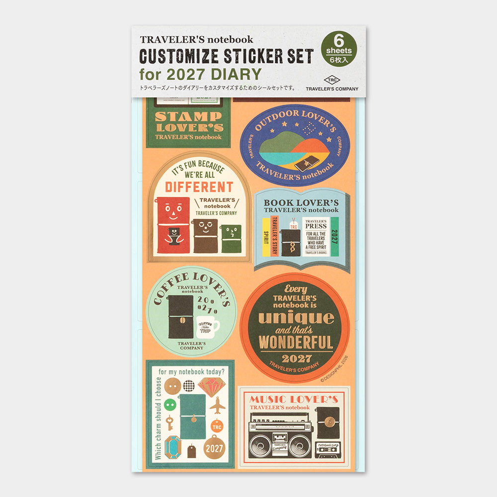 A package of six customizable stickers for a 2027 travel notebook, featuring retro-style circular and rectangular labels with travel-themed designs like 'Stamp Lover's', 'Outdoor Lover's', and 'Book Lover's'.