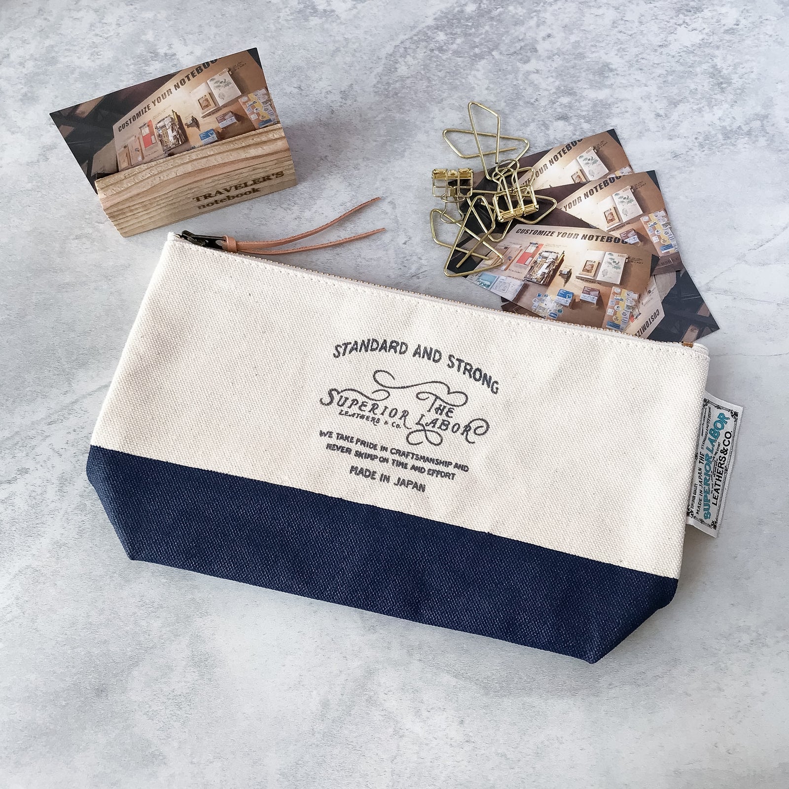 Open view of The Superior Labor navy canvas pouch packed with stationery accessories to show interior storage space.