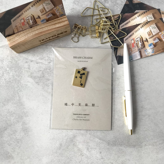 Traveler’s Factory Chichu Art Museum brass charm and packaging in a stationery flat lay
