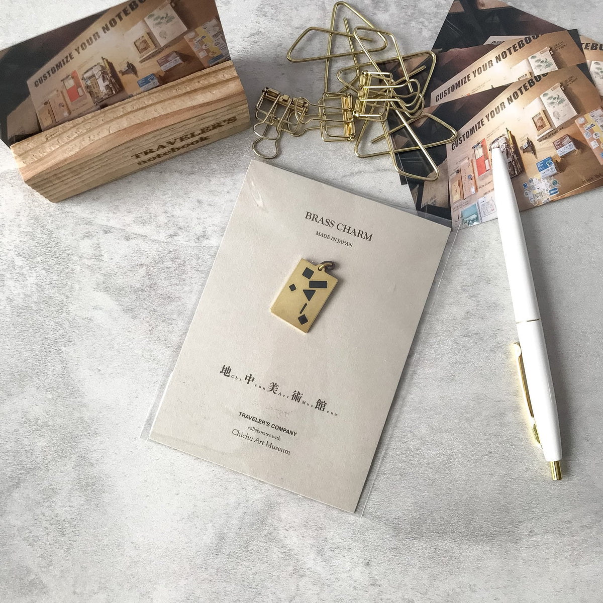 Chichu Art Museum brass charm on its display card beside stationery