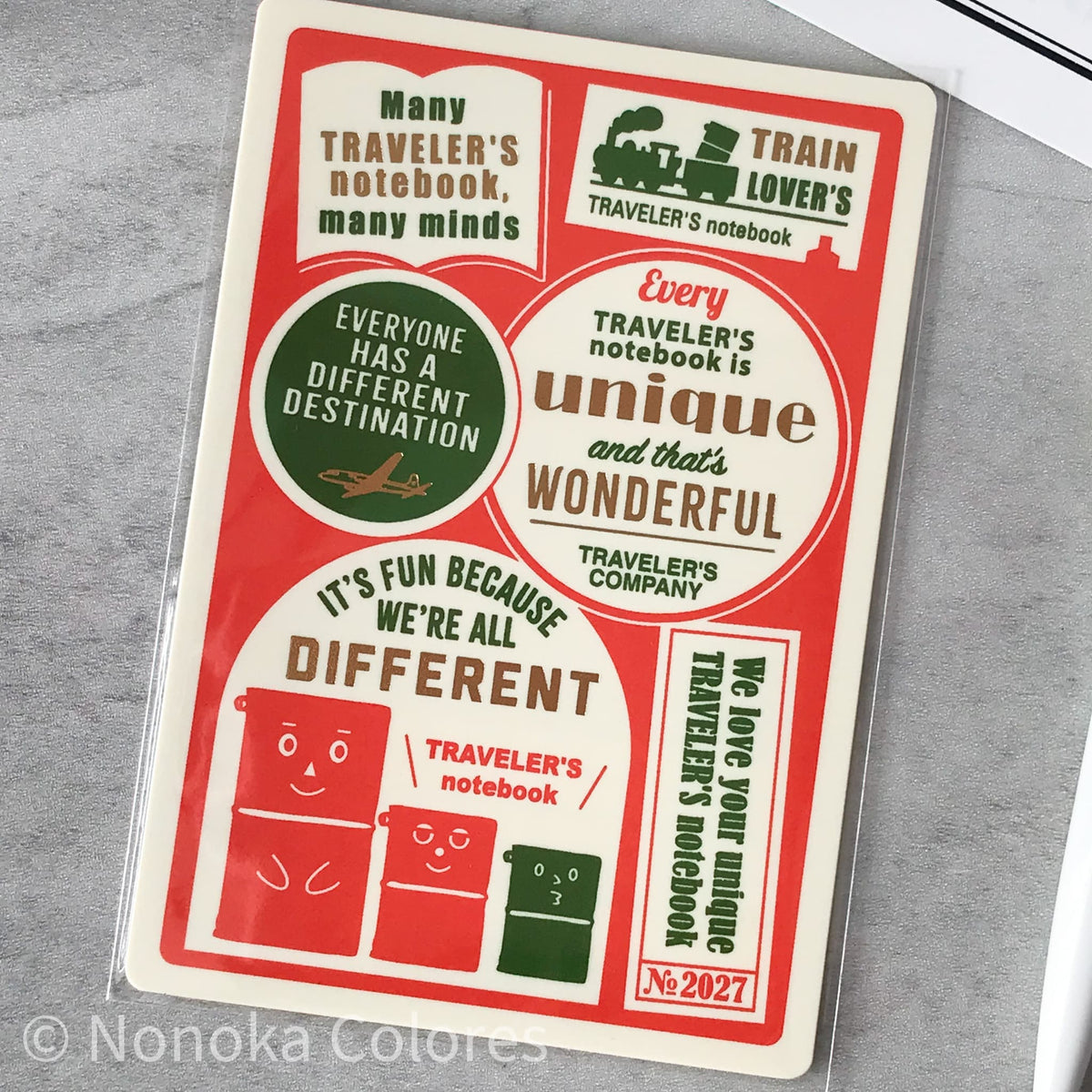 A rectangular sticker sheet or decal pack with travel-themed text and cartoon illustrations, photographed on a gray textured surface. The design is primarily red, cream, and dark green, with phrases like 'Everyone has a different destination' and 'It's fun because we're all different.