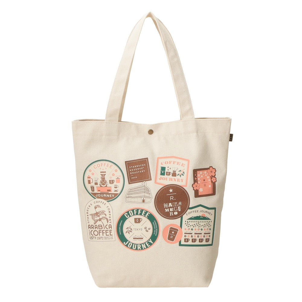 An off-white canvas tote bag with a printed collage of vintage-style coffee-themed stickers in muted green, brown, pink, and orange, shown against a plain white background.